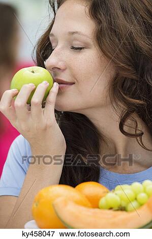 Close-up of a woman smelling a green apple View Large Photo Image Stock Photo - Close-up of a woman smelling a green apple. Fotosearch