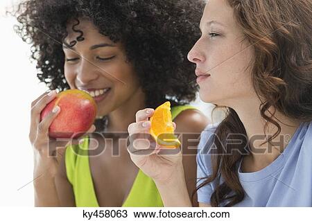 Close-up of two female friends eating fruits View Large Photo Image Stock Image - Close-up of two female friends eating fruits. Fotosearch