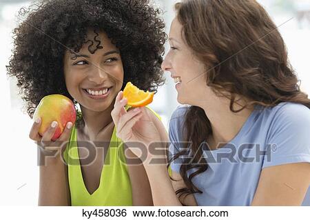 Close-up of two female friends eating fruits View Large Photo Image Stock Photograph - Close-up of two female friends eating fruits. Fotosearch