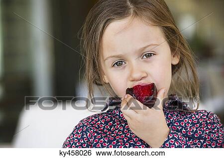 Stock Photograph - Portrait of a girl eating plum. Fotosearch