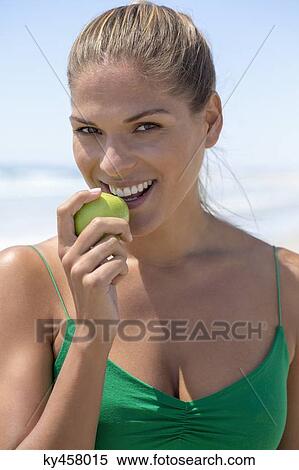 Portrait of a smiling woman eating a green apple View Large Photo Image Stock Photography - Portrait of a smiling woman eating a green apple. Fotosearch