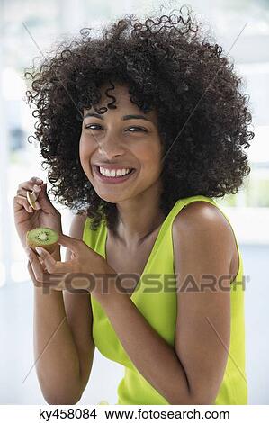 Portrait of a smiling woman eating kiwi fruit with a spoon View Large Photo Image Picture - Portrait of a smiling woman eating kiwi fruit with a spoon. Fotosearch