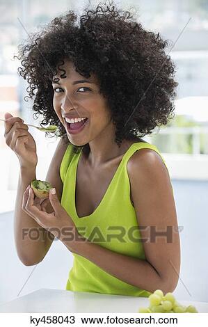 Portrait of a smiling woman eating kiwi fruit with a spoon View Large Photo Image Stock Image - Portrait of a smiling woman eating kiwi fruit with a spoon. Fotosearch