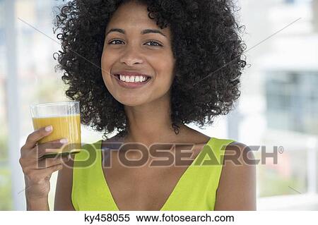 Portrait of a smiling woman holding a glass of mango shake View Large Photo Image Stock Photography - Portrait of a smiling woman holding a glass of mango shake. Fotosearch