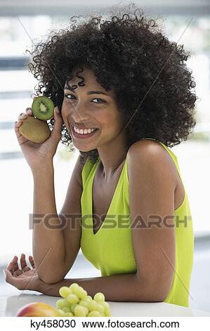 Portrait of a smiling woman showing kiwi fruits View Large Photo Image Stock Image - Portrait of a smiling woman showing kiwi fruits. Fotosearch