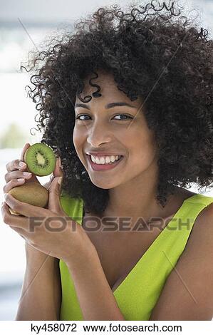 Portrait of a smiling woman showing kiwi fruits View Large Photo Image Stock Image - Portrait of a smiling woman showing kiwi fruits. Fotosearch