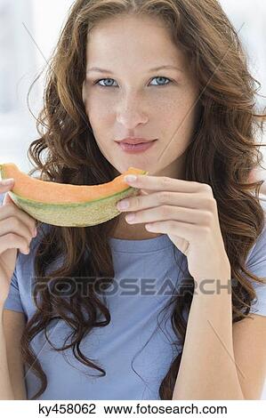 Stock Image - Portrait of a woman eating melon. Fotosearch