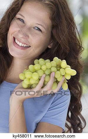 Portrait of a woman holding a bunch of grapes and smiling View Large Photo Image Stock Image - Portrait of a woman holding a bunch of grapes and smiling. Fotosearch