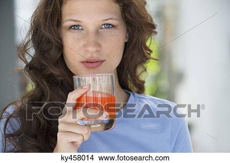 Portrait of a woman holding a glass of orange juice View Large Photo Image Picture - Portrait of a woman holding a glass of orange juice. Fotosearch