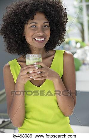 Stock Photograph - Portrait of a woman holding a glass of kiwi juice. Fotosearch