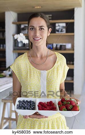 Portrait of a woman holding a tray of assorted berries at home View Large Photo Image Stock Photography - Portrait of a woman holding a tray of assorted berries at home. Fotosearch