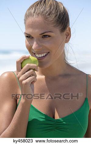 Smiling woman eating a green apple View Large Photo Image Stock Image - Smiling woman eating a green apple. Fotosearch