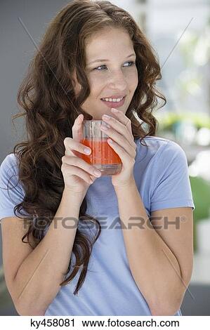 Smiling woman holding a glass of orange juice View Large Photo Image Stock Image - Smiling woman holding a glass of orange juice. Fotosearch