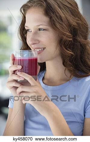 Smiling woman holding a glass of pomegranate juice View Large Photo Image Stock Image - Smiling woman holding a glass of pomegranate juice. Fotosearch