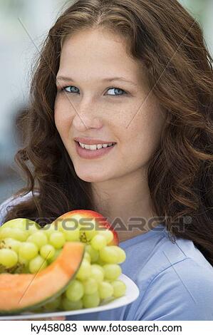 Smiling woman holding a plate of fruits View Large Photo Image Stock Image - Smiling woman holding a plate of fruits. Fotosearch