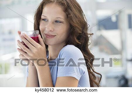 Stock Image - Woman holding a glass of pomegranate juice. Fotosearch