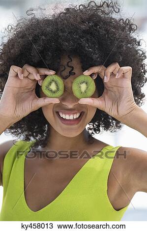 Woman holding kiwi fruits in front of her eyes View Large Photo Image Stock Image - Woman holding kiwi fruits in front of her eyes. Fotosearch