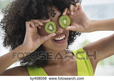 Woman holding kiwi fruits in front of her eyes View Large Photo Image Stock Photo - Woman holding kiwi fruits in front of her eyes. Fotosearch
