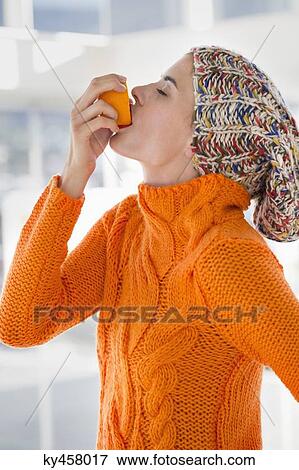 Stock Photo - Woman squeezing juice from an orange into her mouth. Fotosearch