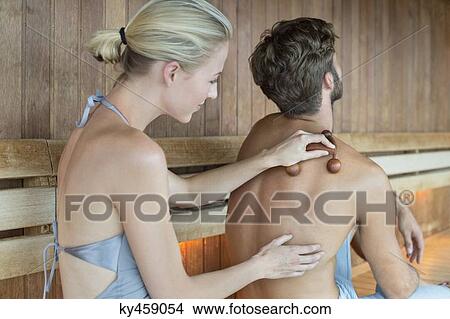 Woman massaging on her friend's back with a massager in a sauna View Large Photo Image Picture - Woman massaging on her friend's back with a massager in a sauna. Fotosearch