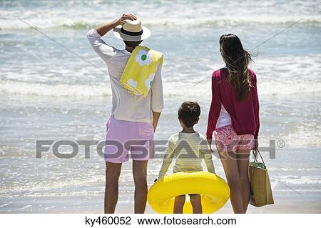 Stock Image - Boy with his parents looking at sea on the beach. Fotosearch