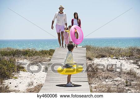 Children with their parents holding inflatable rings on a boardwalk on the beach View Large Photo Image Stock Photograph - Children with their parents holding inflatable rings on a boardwalk on the beach. Fotosearch
