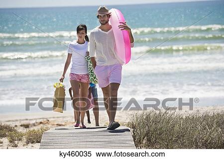 Stock Photography - Family walking on a boardwalk on the beach. Fotosearch