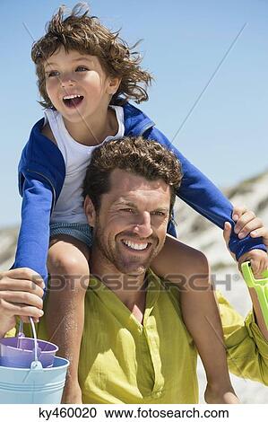Man carrying his son on shoulders on the beach View Large Photo Image Stock Image - Man carrying his son on shoulders on the beach. Fotosearch