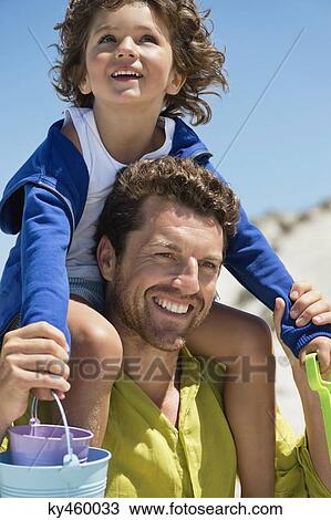 Man carrying his son on shoulders on the beach View Large Photo Image Stock Image - Man carrying his son on shoulders on the beach. Fotosearch