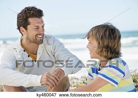 Stock Photo - Man sitting with his son on the beach. Fotosearch