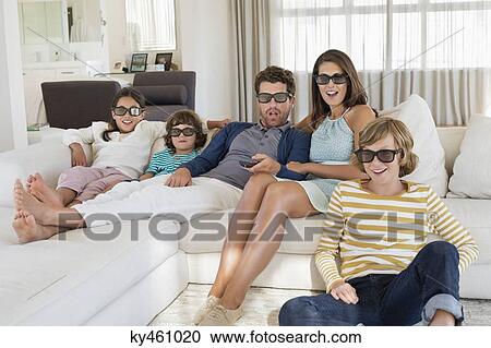 Family watching television at home while wearing 3D glasses View Large Photo Image Stock Image - Family watching television at home while wearing 3D glasses. Fotosearch