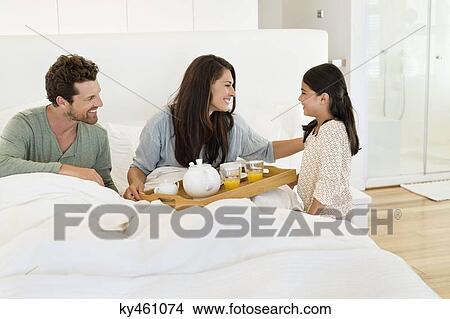 Girl serving tea to her parents on the bed View Large Photo Image Picture - Girl serving tea to her parents on the bed. Fotosearch