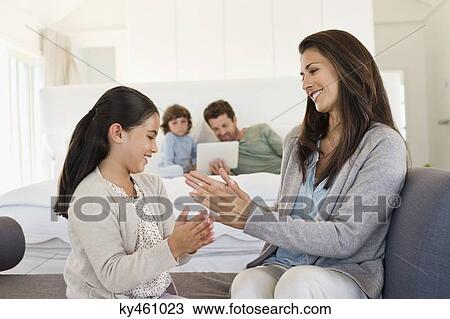Stock Image - Mother and her daughter playing Pat-a-cake and smiling. Fotosearch