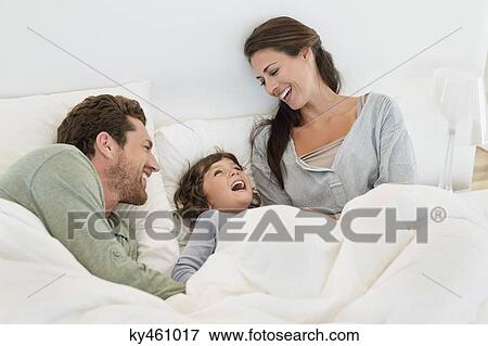 Stock Photo - Parents playing with their son on the bed. Fotosearch