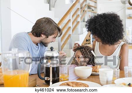 Picture - Parents with their daughter at a dining table. Fotosearch