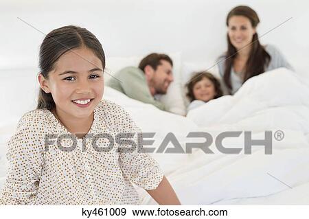 Stock Photo - Portrait of a girl smiling with her family in the background. Fotosearch