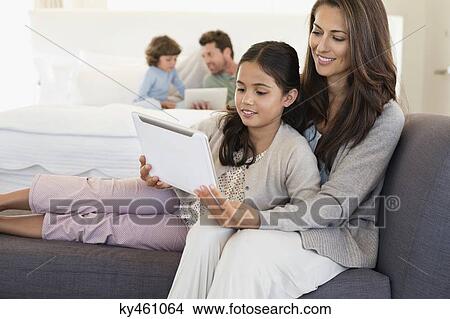 Woman and her daughter looking at a digital tablet View Large Photo Image Picture - Woman and her daughter looking at a digital tablet. Fotosearch