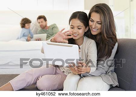 Woman and her daughter looking at a digital tablet View Large Photo Image Stock Image - Woman and her daughter looking at a digital tablet. Fotosearch