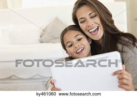 Woman and her daughter looking at a digital tablet View Large Photo Image Stock Image - Woman and her daughter looking at a digital tablet. Fotosearch