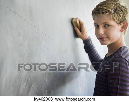 Boy cleaning blackboard with a duster in a classroom View Large Photo Image Stock Image - Boy cleaning blackboard with a duster in a classroom. Fotosearch