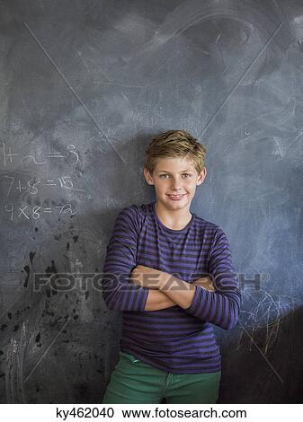 Boy smiling with his arms crossed in front of a blackboard in a classroom View Large Photo Image Stock Image - Boy smiling with his arms crossed in front of a blackboard in a classroom. Fotosearch