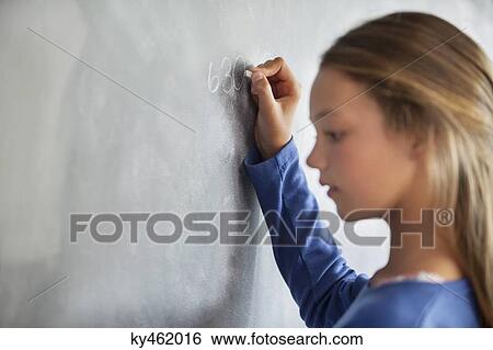 Close-up of a girl writing on a blackboard in a classroom View Large Photo Image Stock Photograph - Close-up of a girl writing on a blackboard in a classroom. Fotosearch