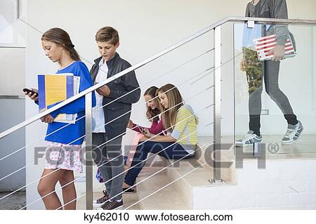 Stock Image - Students using electronic gadget in a school. Fotosearch
