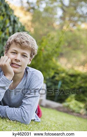 Teenage boy lying on grass View Large Photo Image Stock Image - Teenage boy lying on grass. Fotosearch