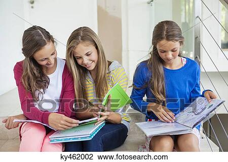Three girls sitting on stairs and studying in a school View Large Photo Image Stock Image - Three girls sitting on stairs and studying in a school. Fotosearch
