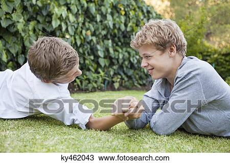 Two boys arm wrestling on grass View Large Photo Image Stock Image - Two boys arm wrestling on grass. Fotosearch