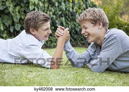Stock Photo - Two boys arm wrestling on grass. Fotosearch