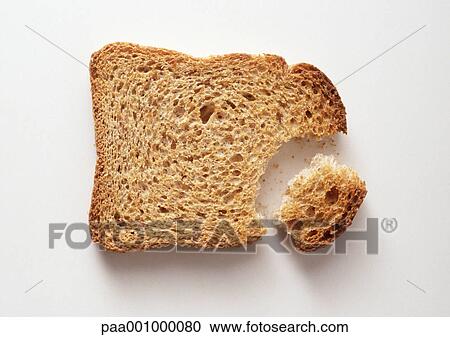 Stock Image - Slice of bread with piece broken off, close-up. Fotosearch
