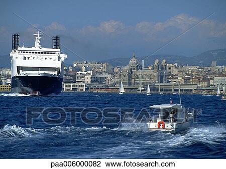 Ferry next to smaller moving boat, coastal city in background View Large Photo Image Stock Image - Ferry next to smaller moving boat, coastal city in background. Fotosearch