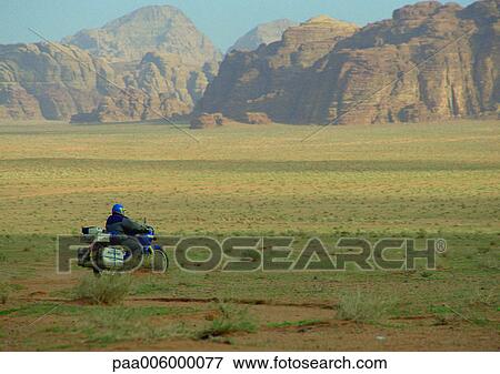 Stock Photo - Jordan, motorcyclist riding through mountainous region.. Fotosearch